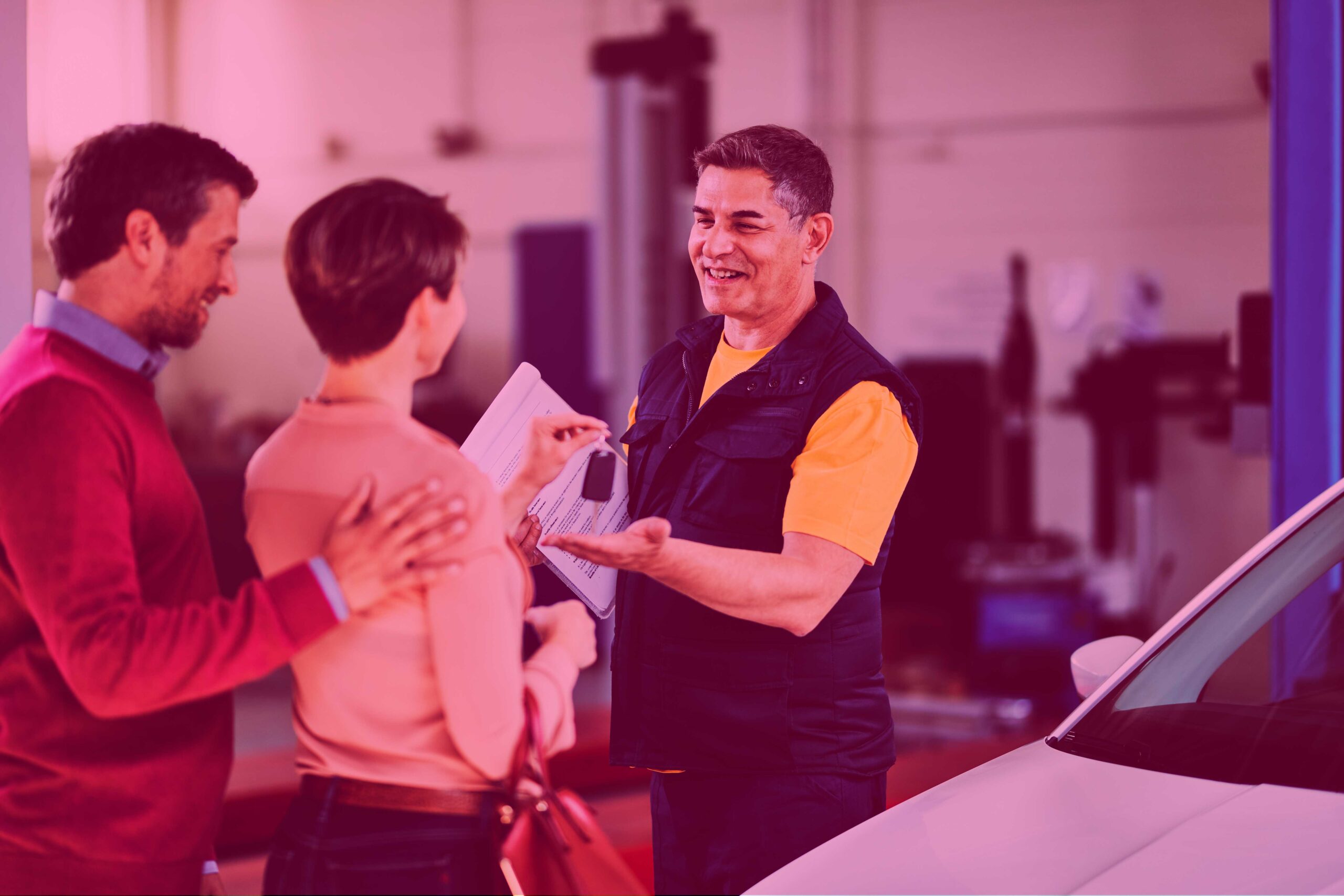 Happy auto repairman receiving car key from his customers in a w